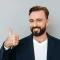 compressed_cheerful-bearded-man-busines-clothes-showing-thumb-up-looking-camera-gray